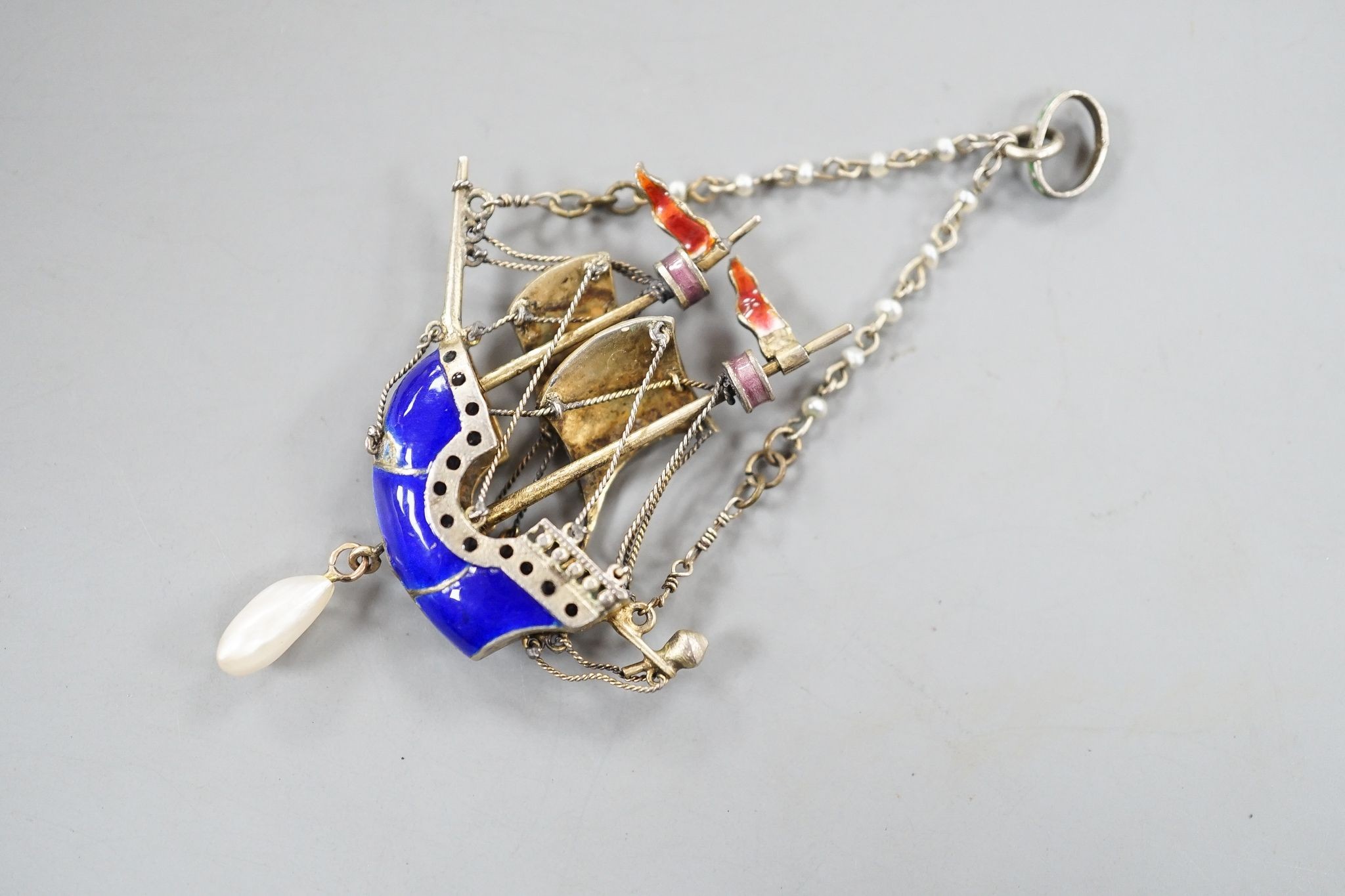 A 20th century continental gilt white metal, polychrome enamel, seed and baroque pearl set 'sailing ship' drop pendant, 48mm.